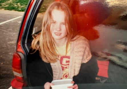 Lucy Nichol as a teenager sitting at the back of a hatchback car - with long fair hair staring at camera