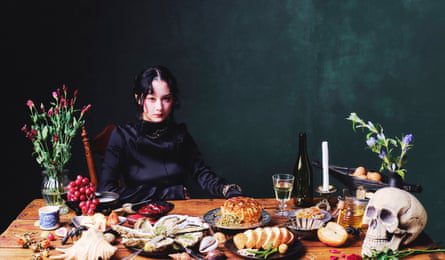 Japanese Breakfast’s lead singer, Michelle Zauner, sitting at a table laden with food, flowers and a skull.