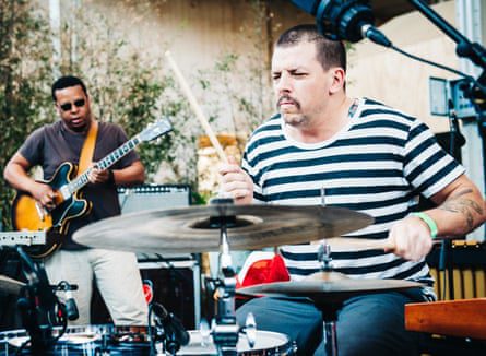 Parker playing guitar, with Herndon holding a drumstick over a cymbal in the foreground