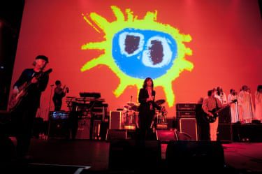 Primal Scream perform in front of a large projection of the Screamadelica artwork.
