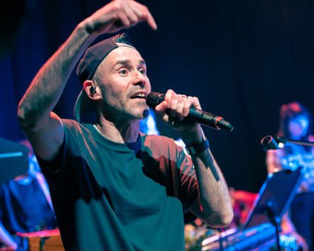 Man in reversed baseball cap raps on stage