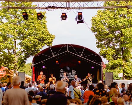 A small stage between two trees with musicians on it.